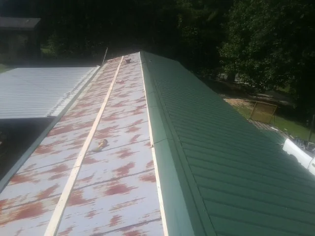 Old rusted panels beside newly installed green metal roofing — Wind Damage Roof Repair by Roofing Brothers in Bridgeton