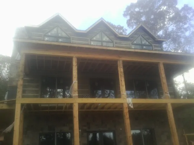 Dormers and porch framing on a large log home under construction — Roof Coating work by our crew in Bridgeton