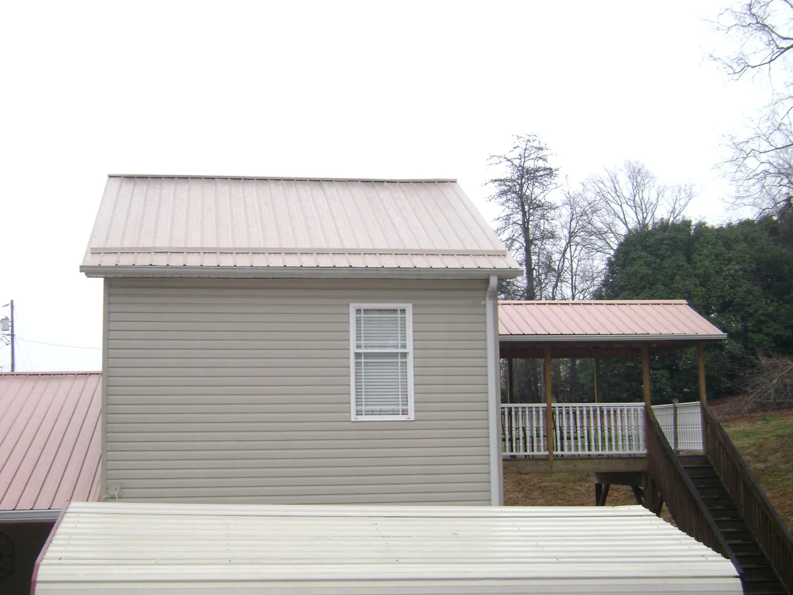 Tan metal roofs on a two story addition and attached porch, from a Roof Replacement job in Bridgeton
